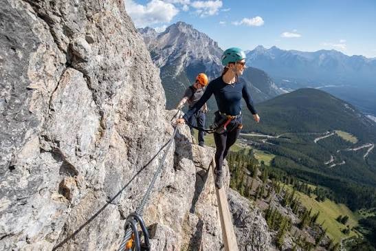 Une personne fait de la via ferrata sur une paroi rocheuse.